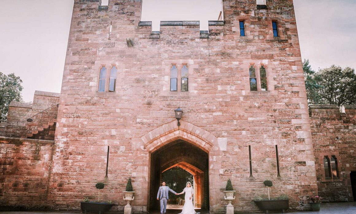 Asian groom and bride entering at Peckforton Castle.