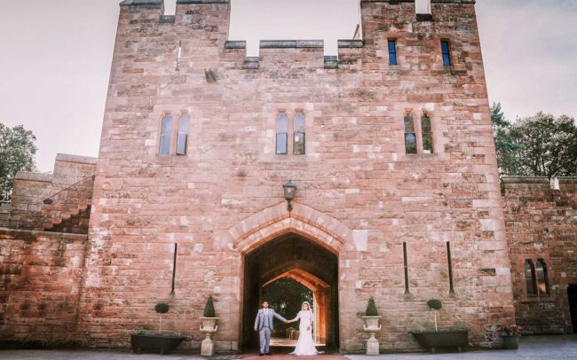 Asian groom and bride entering at Peckforton Castle.